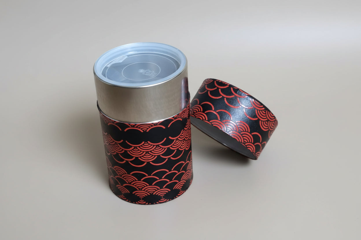 Red and black patterned container with a silver lid on a woven mat
