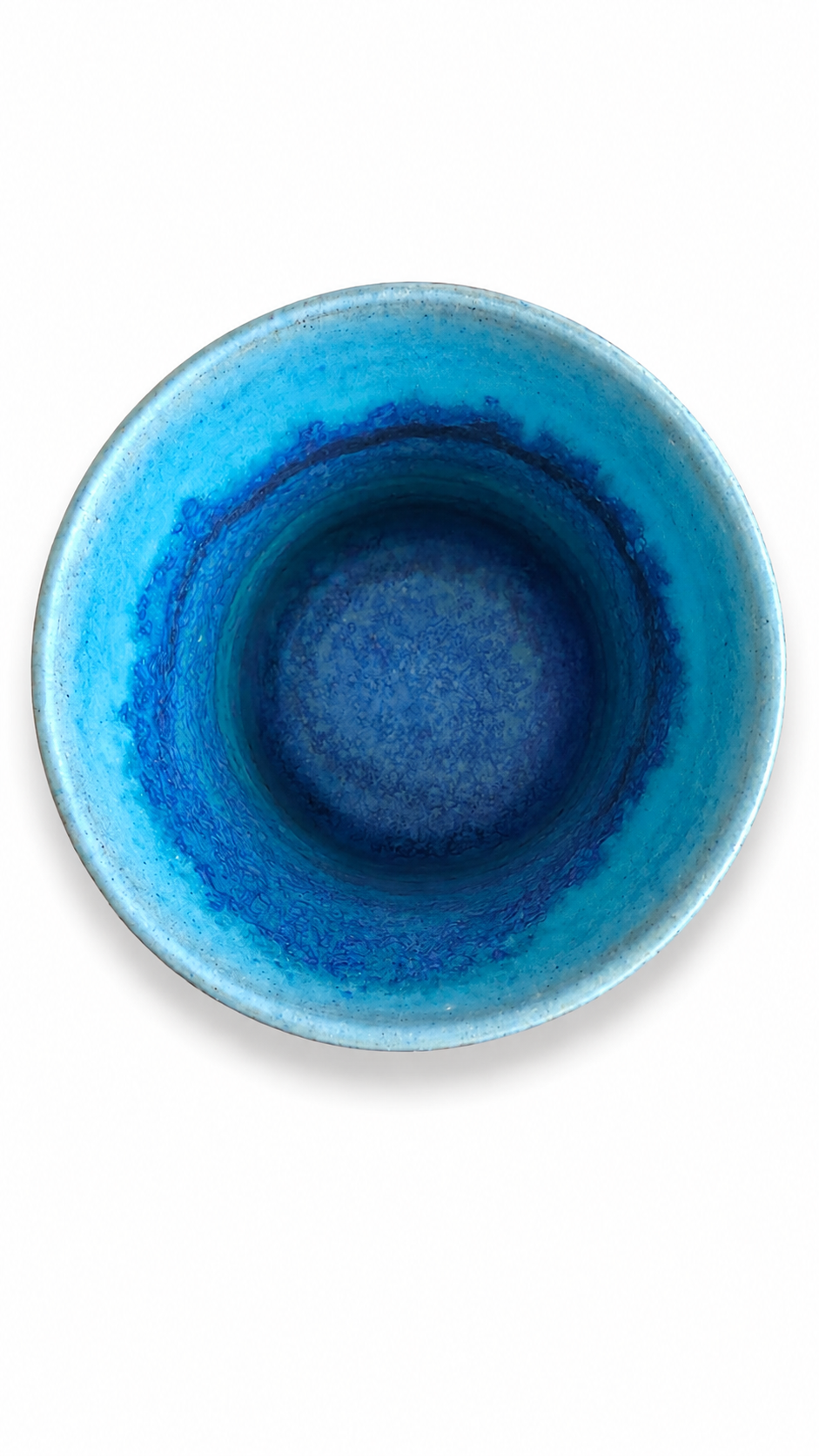 Interior of artisan Japanese tea cup showing deep indigo and turquoise kiln-fired glaze effects.